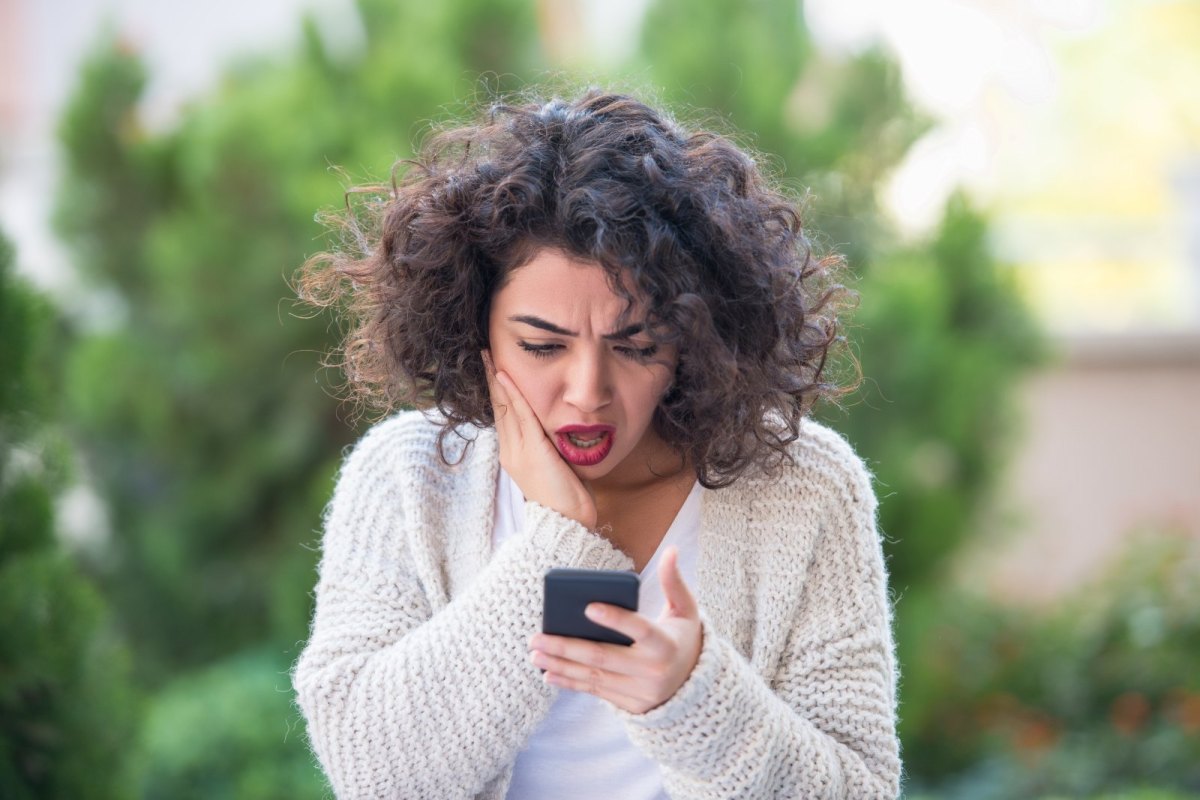 Frau schaut äußerst besorgt auf ihr Handy.