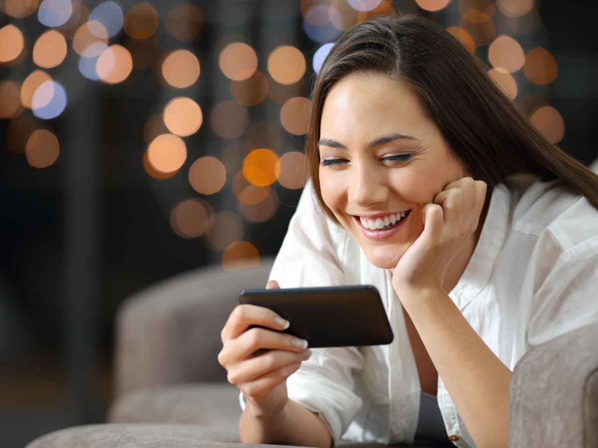 Frau guckt auf ihr Handy und freut sich