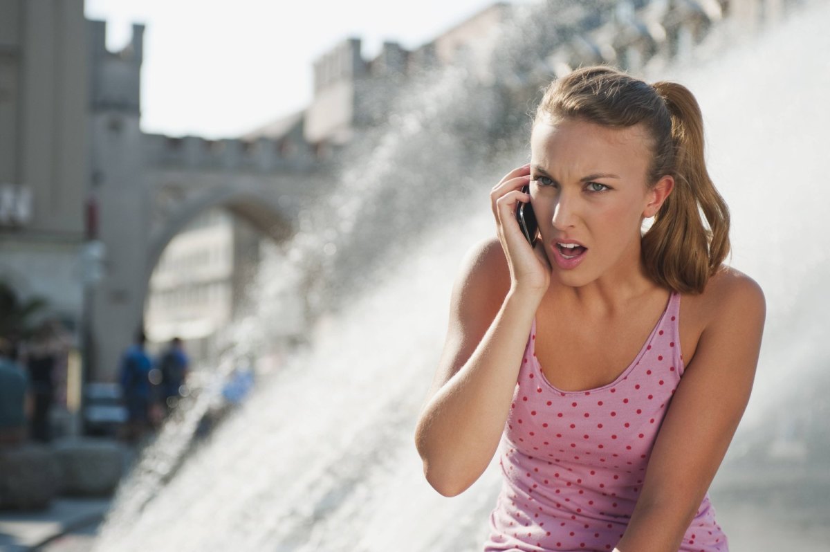 Frau hält verärgert ihr Handy ans Ohr.