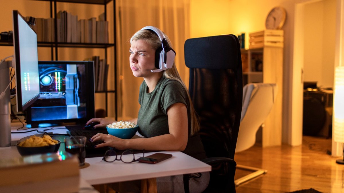 Frau sitzt vor dem PC mit Headset.