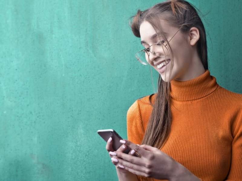 Eine Frau schaut auf ihr Smartphone in ihren Händen.