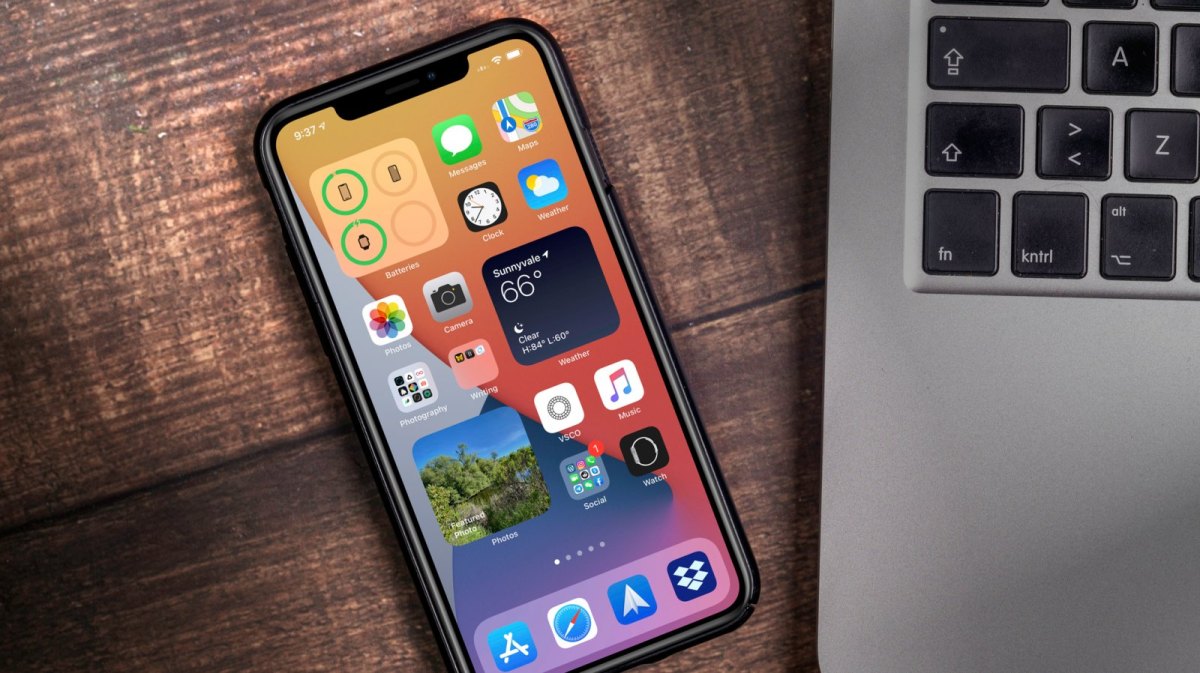 iPhone mit iOS 14 neben einem MacBook.