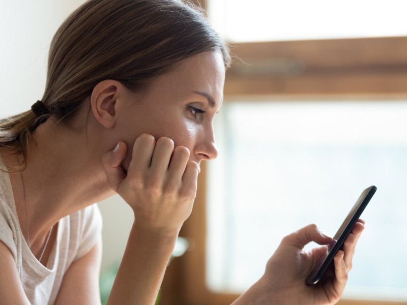 Frau schaut kritisch auf ihr Handy.