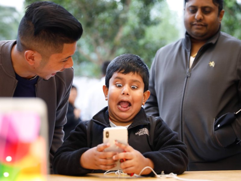 Junge hält iPhone X in der Hand und verzerrt das Gesicht