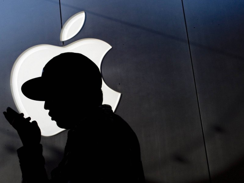 Silhouette von Mann mit iPhone vor Apple Logo.