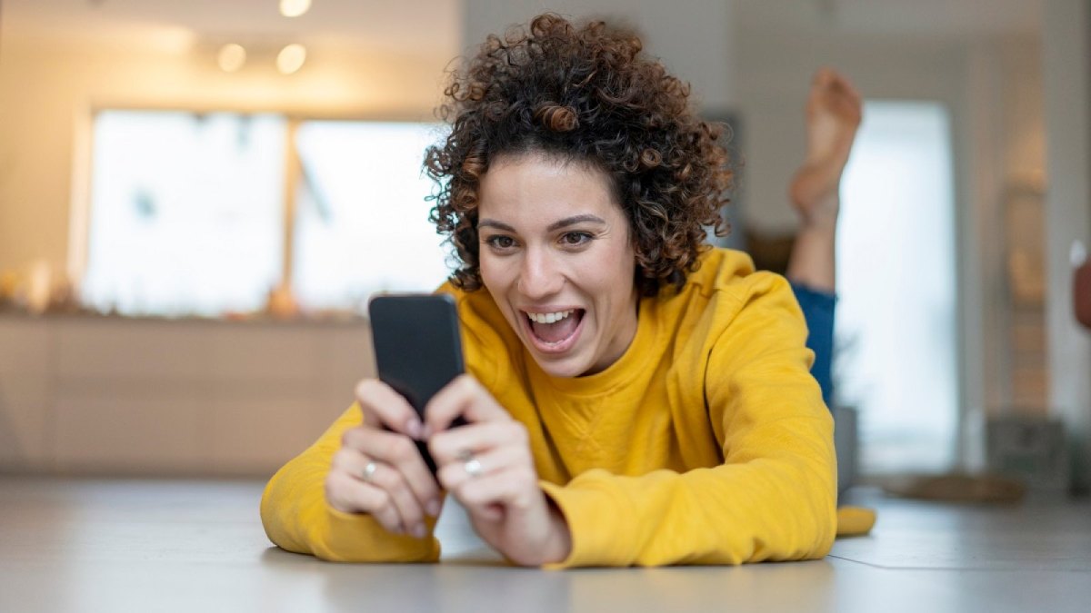 Frau schaut begeistert auf ihr Handy.