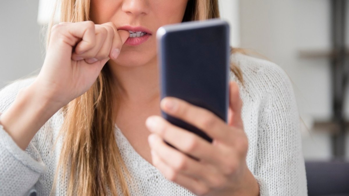 Frau blickt besorgt auf ihr Handy.