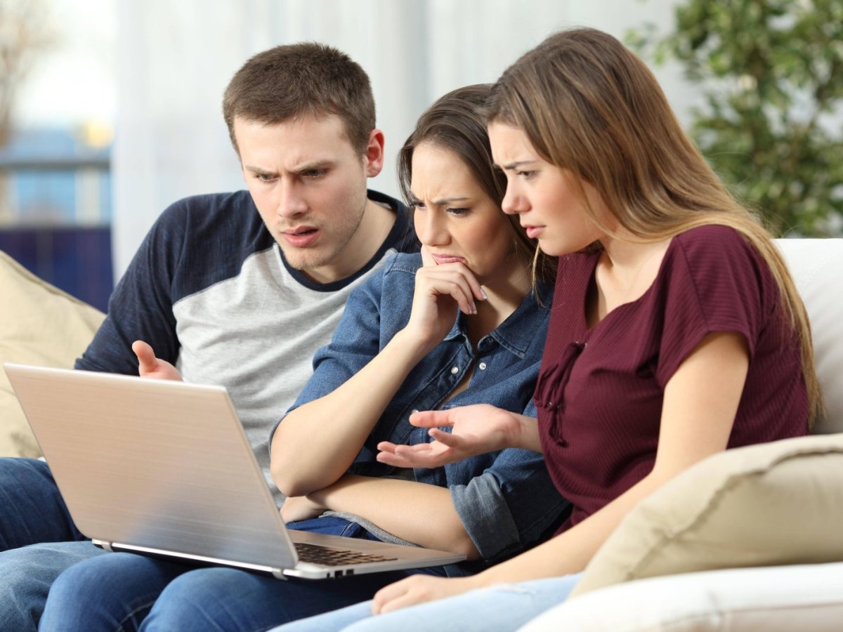 drei Freunde schauen frustriert auf Laptop