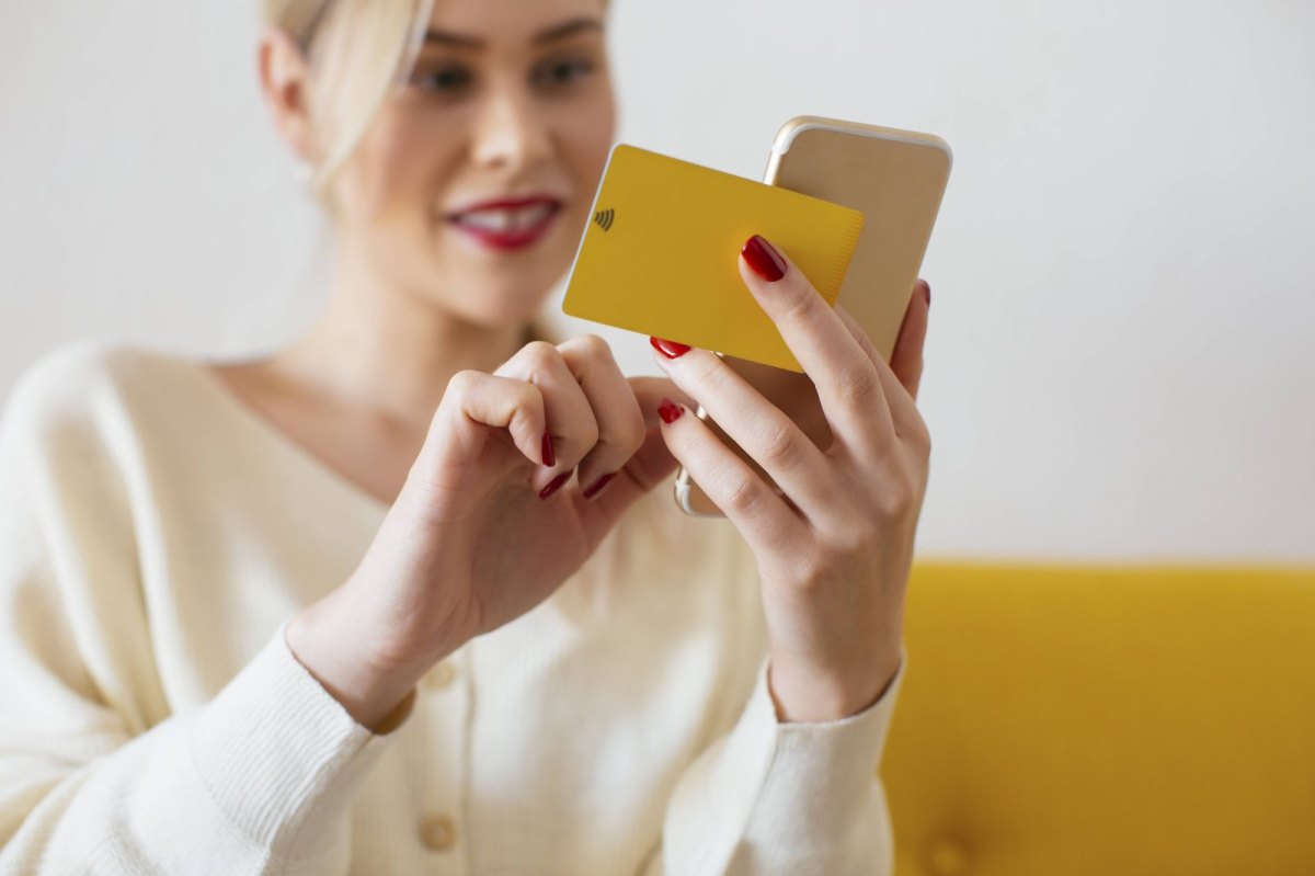 Frau hält Handy und Kreditkarte in der Hand.