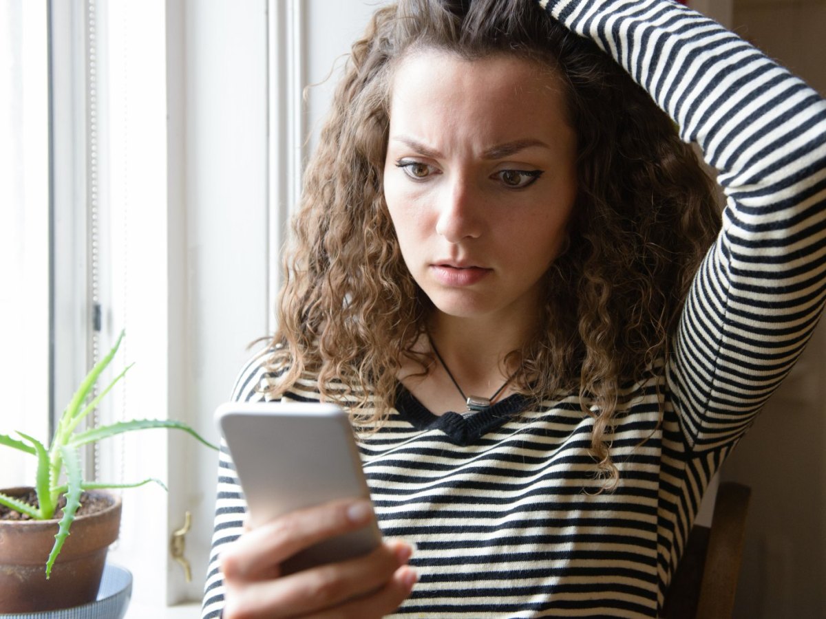 Frau schaut geschockt auf ihr Handy.