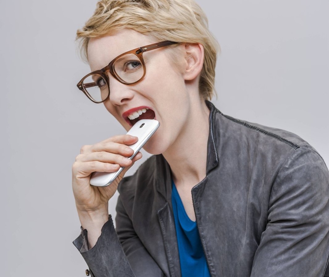 Frau beißt auf Smartphone