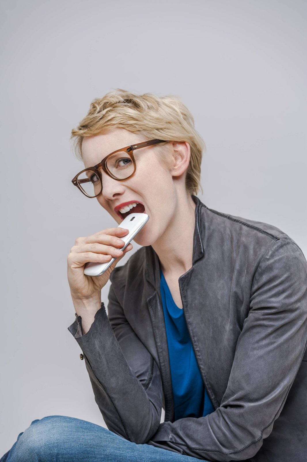 Frau beißt auf Smartphone