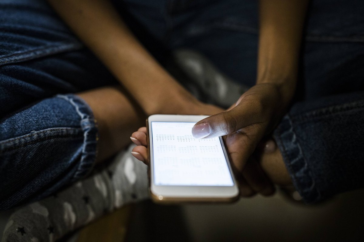 Frau im Schneidersitz hält Smartphone in der Hand