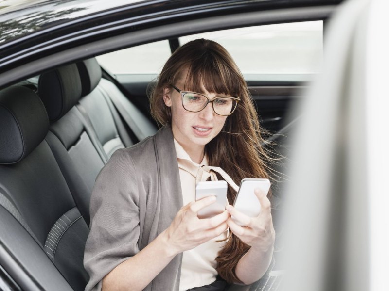 Frau schaut ratlos auf Smartphones