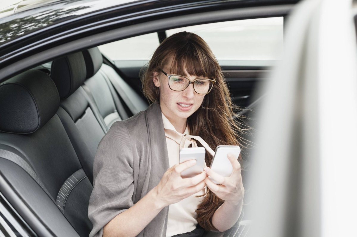 Frau schaut ratlos auf Smartphones