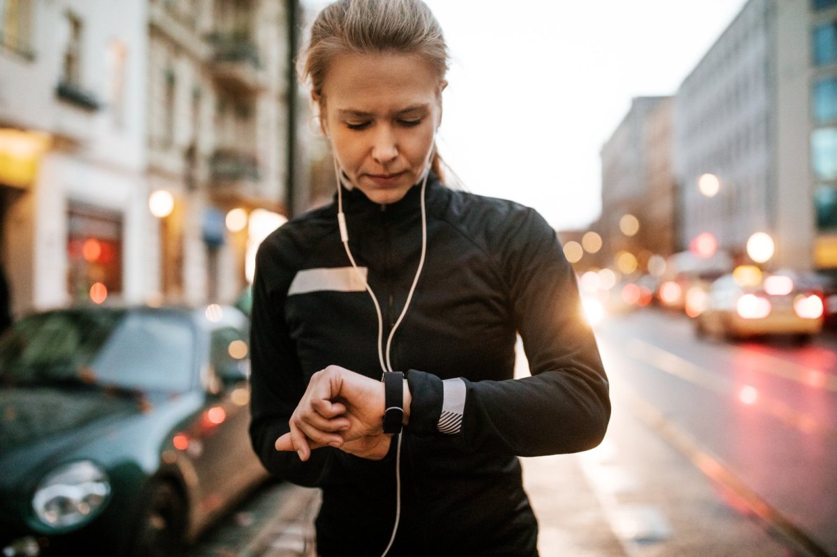 Frau mit Smartwatch und Kopfhörern auf der Straße.