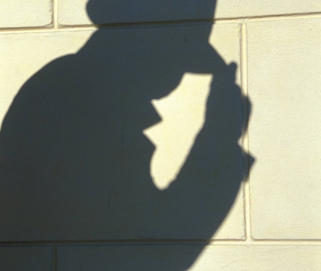 Der Schatten einer Person mit Mantel und Hut