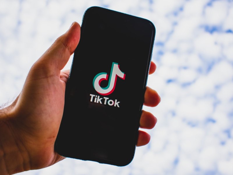 Eine Hand mit einem Smartphone auf dem das TikTok-Logo zu sehen ist.