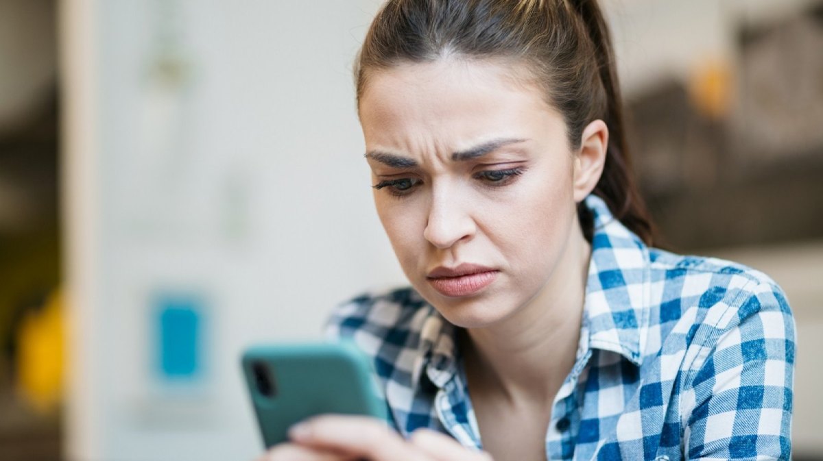 Frau schaut fragend auf ihr Handy.