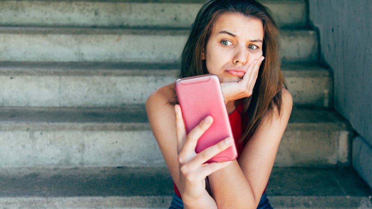 Frau blickt unzufrieden auf ihr Handy.