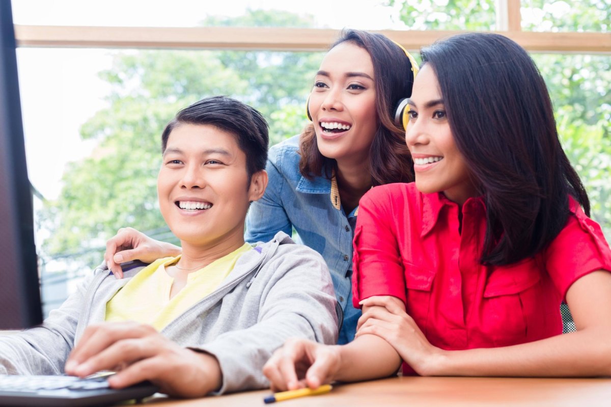 drei freunde lachen über inhalte auf dem pc