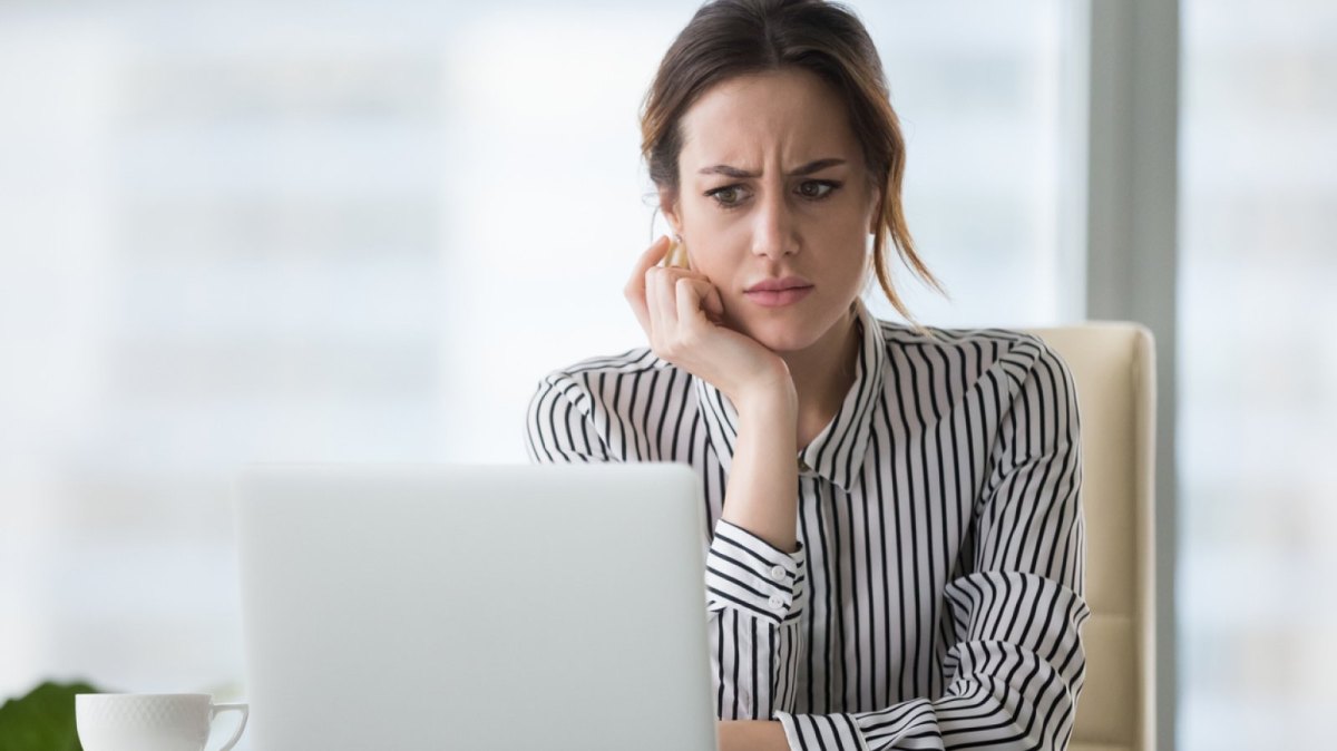 Frau sieht genervt auf ihren Laptop.