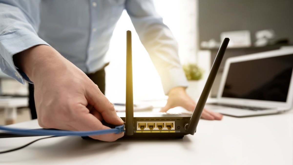 Mann stöpselt WLAN an Router an