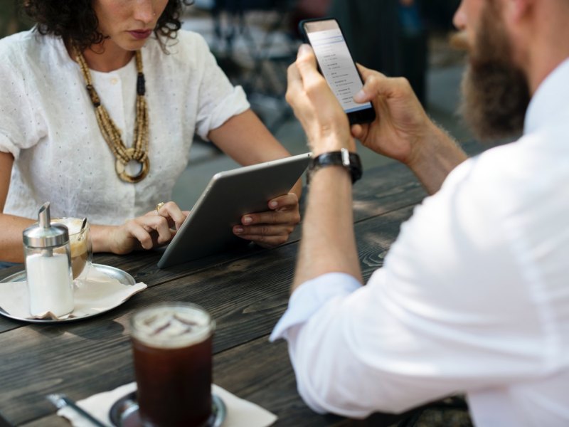 Personen halten Tablet und Handy in den Händen