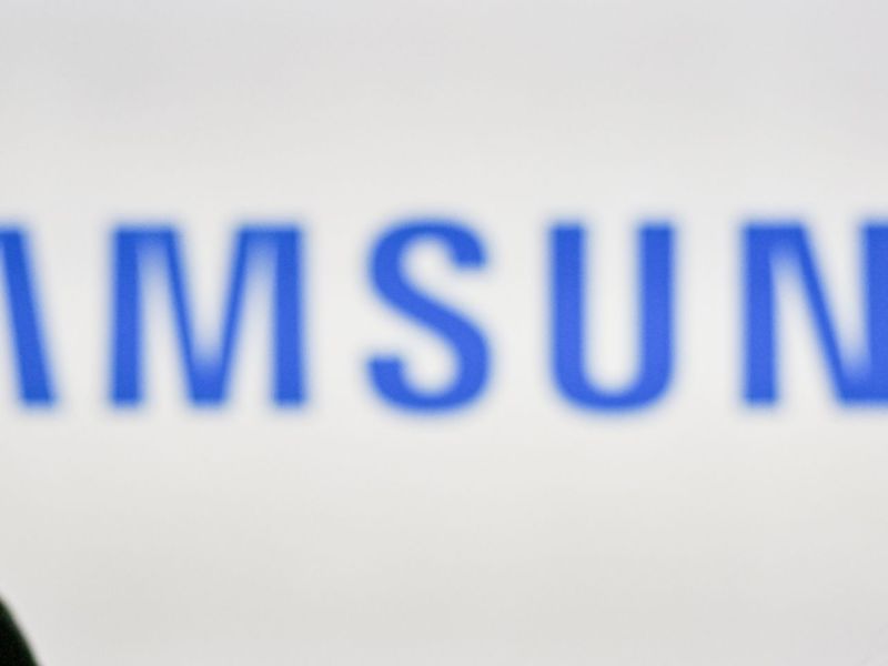 Frau mit Smartphone vor einem Samsung-Logo