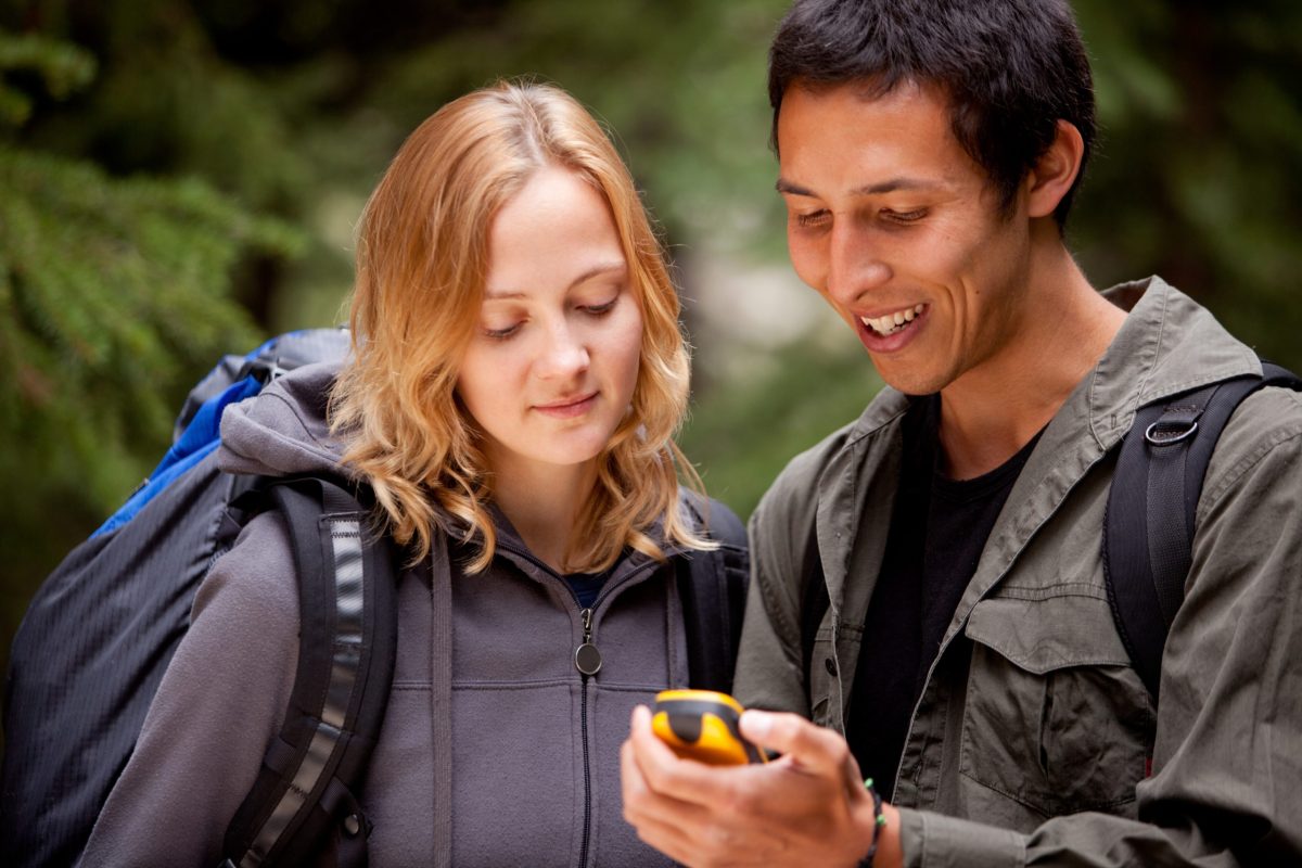 Mann und Frau gucken in Natur auf Handy