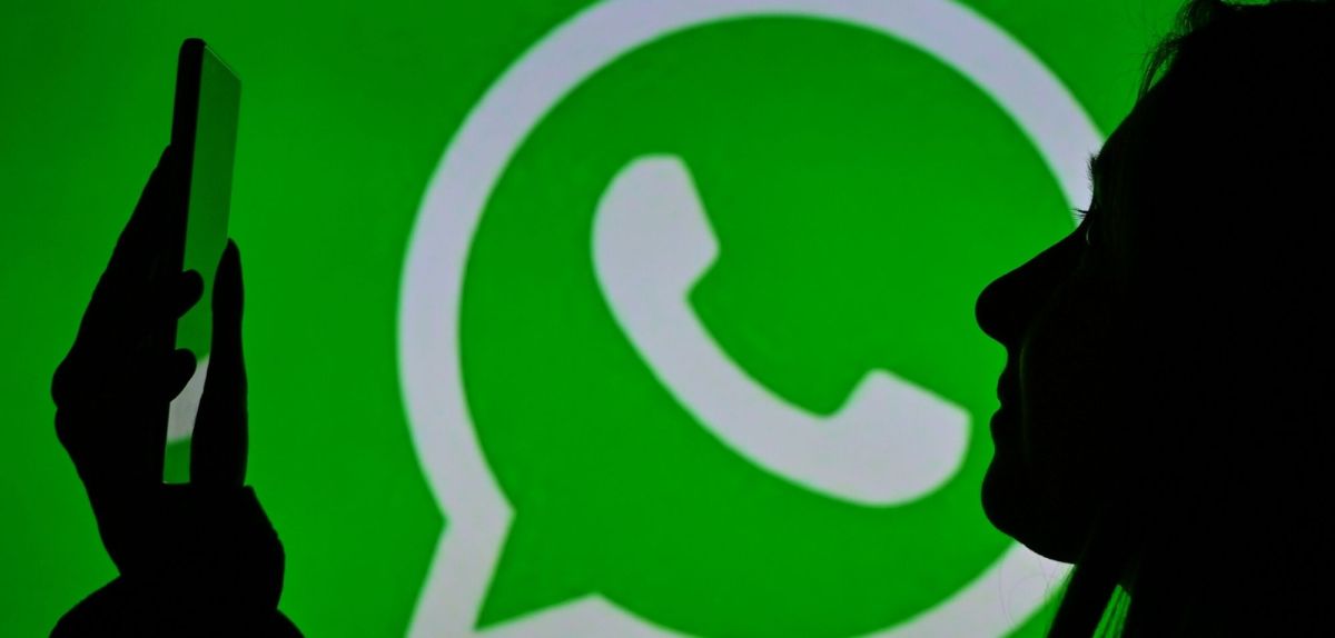 Frau mit Smartphone vor einem WhatsApp-Logo