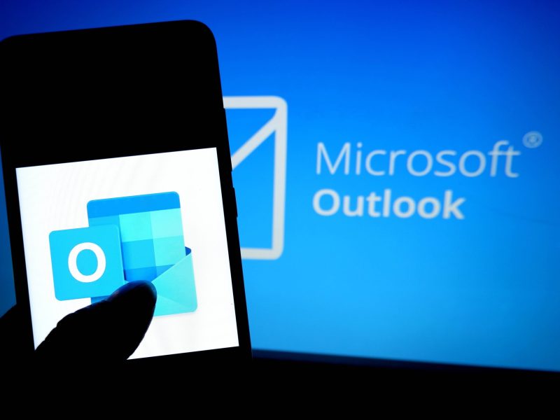 Handy mit Outlook App vor Bildschirm