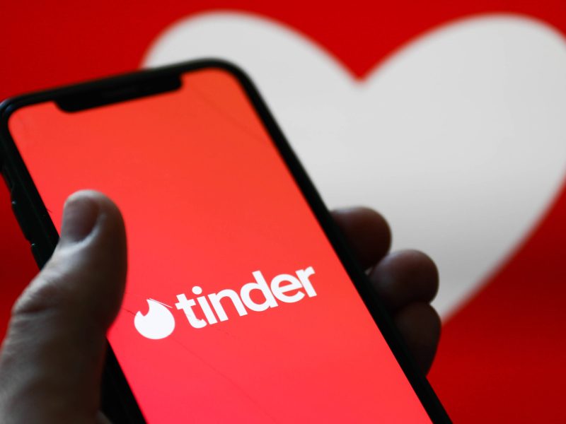 Tinder-App auf Smartphone vor Herzsymbol