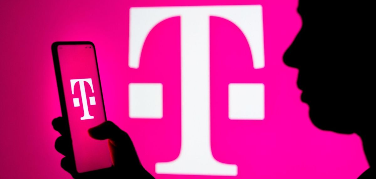 Person mit Smartphone vor einem Telekom-Logo