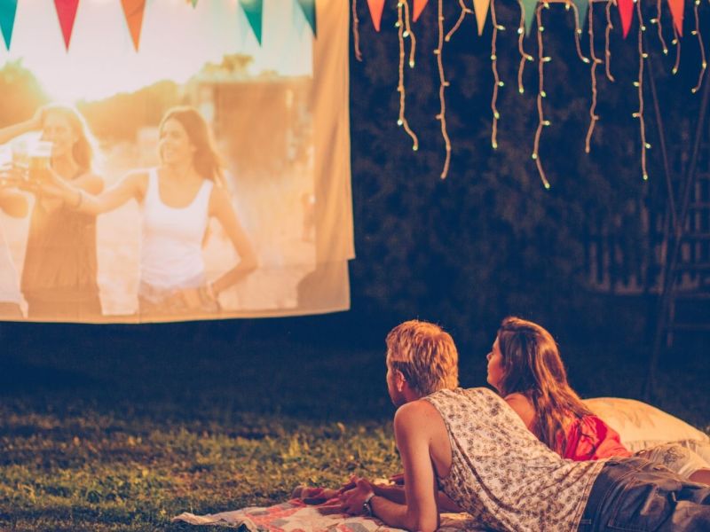 Paar liegt auf der Wiese vor einer Filmleinwand.