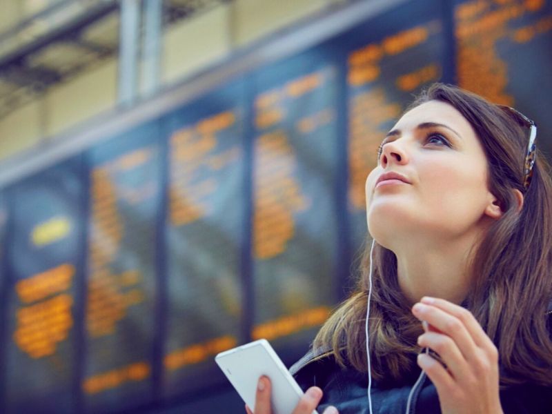 Frau mit Handy am Bahnhof