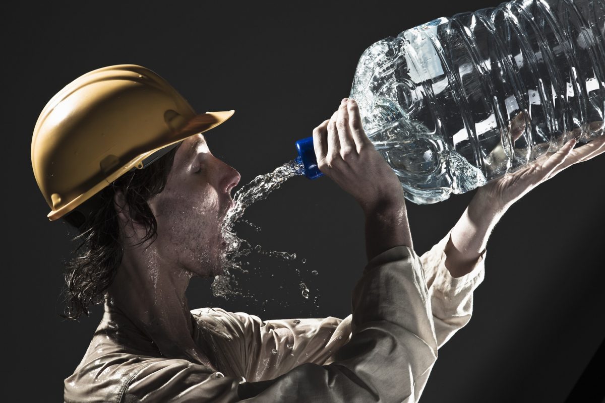 Mann trinkt Wasser aus einer großen Flasche