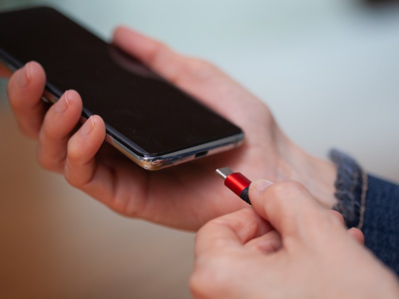 Ein Ladekabel wird an ein Handy und dessen Akku angeschlossen