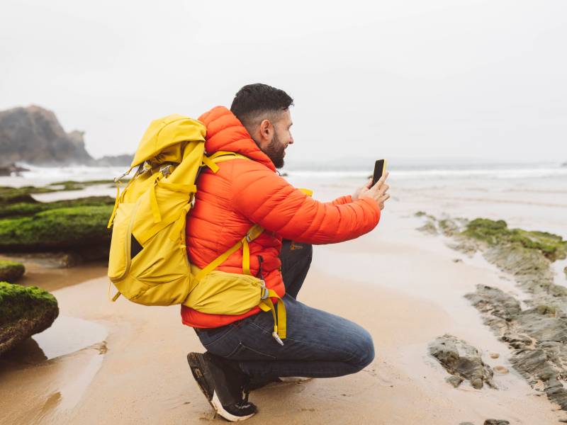 Outdoor-Handy wird von Mann zum Fotografieren an Küste genutzt