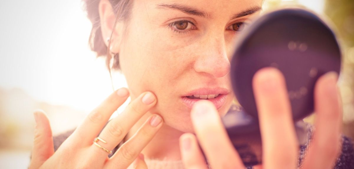 Frau schaut in einen Makeup-Spiegel