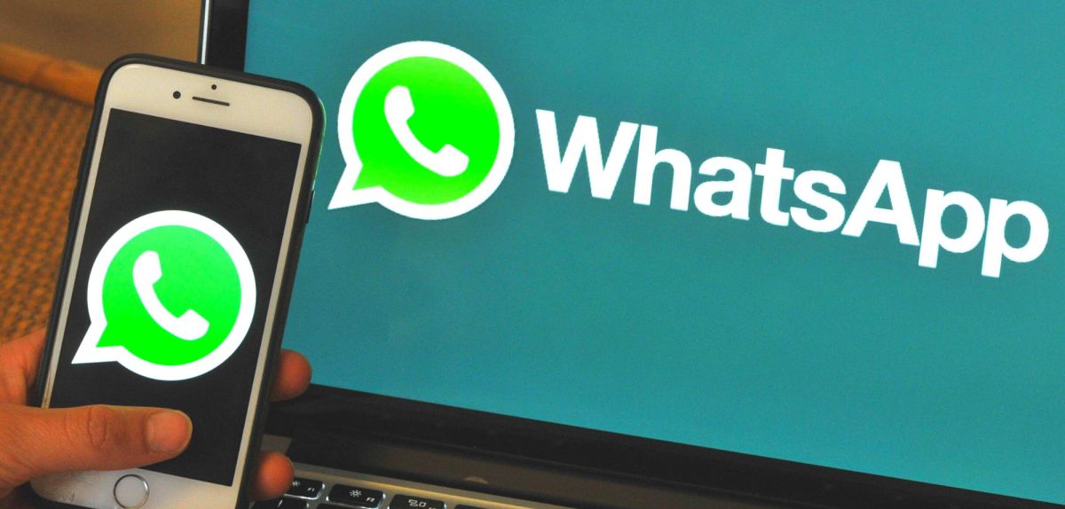 Handy mit WhatsApp-Logo vor Laptop mit demselben Logo.