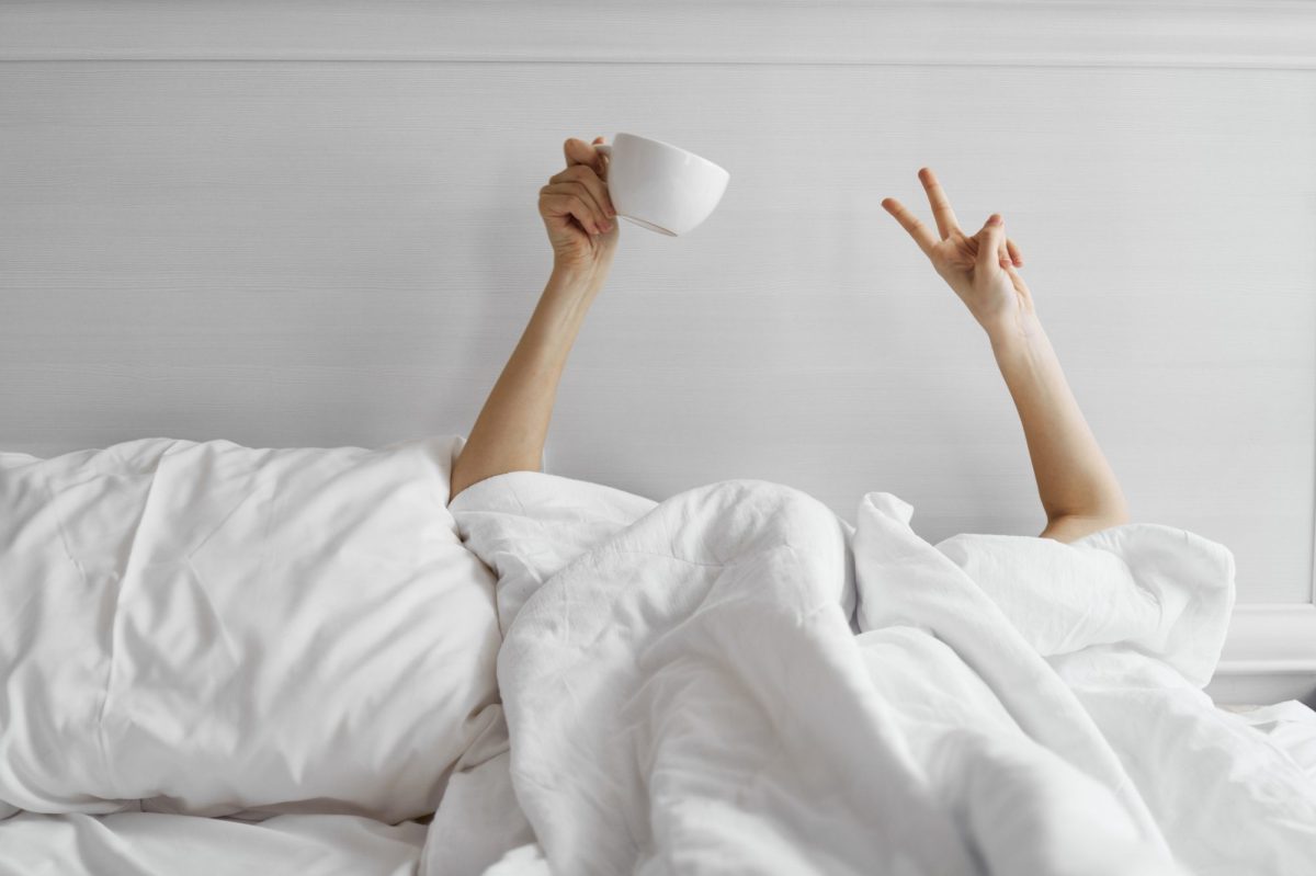 Frau im Bett mit Kaffeetasse