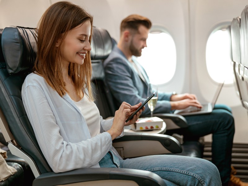 Frau mit Handy und WLAN im Flieger