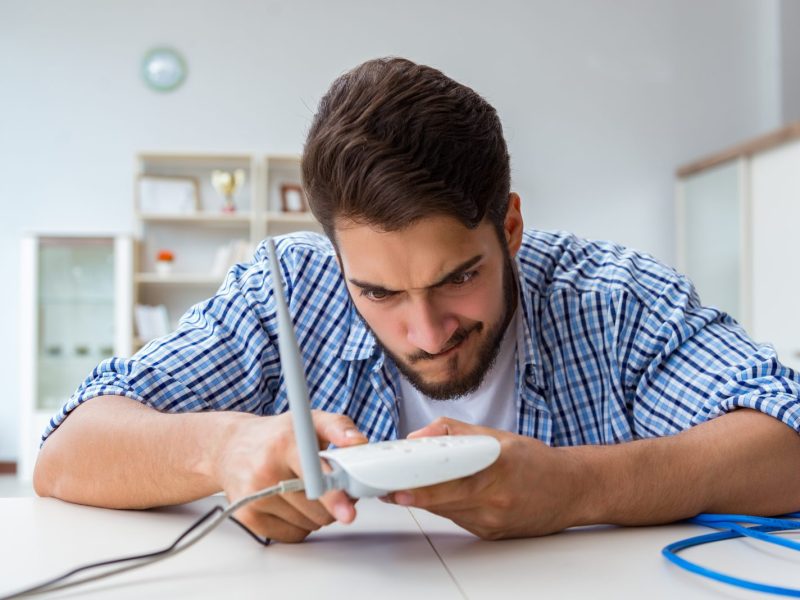 Mann hält WLAN-Router in der Hand