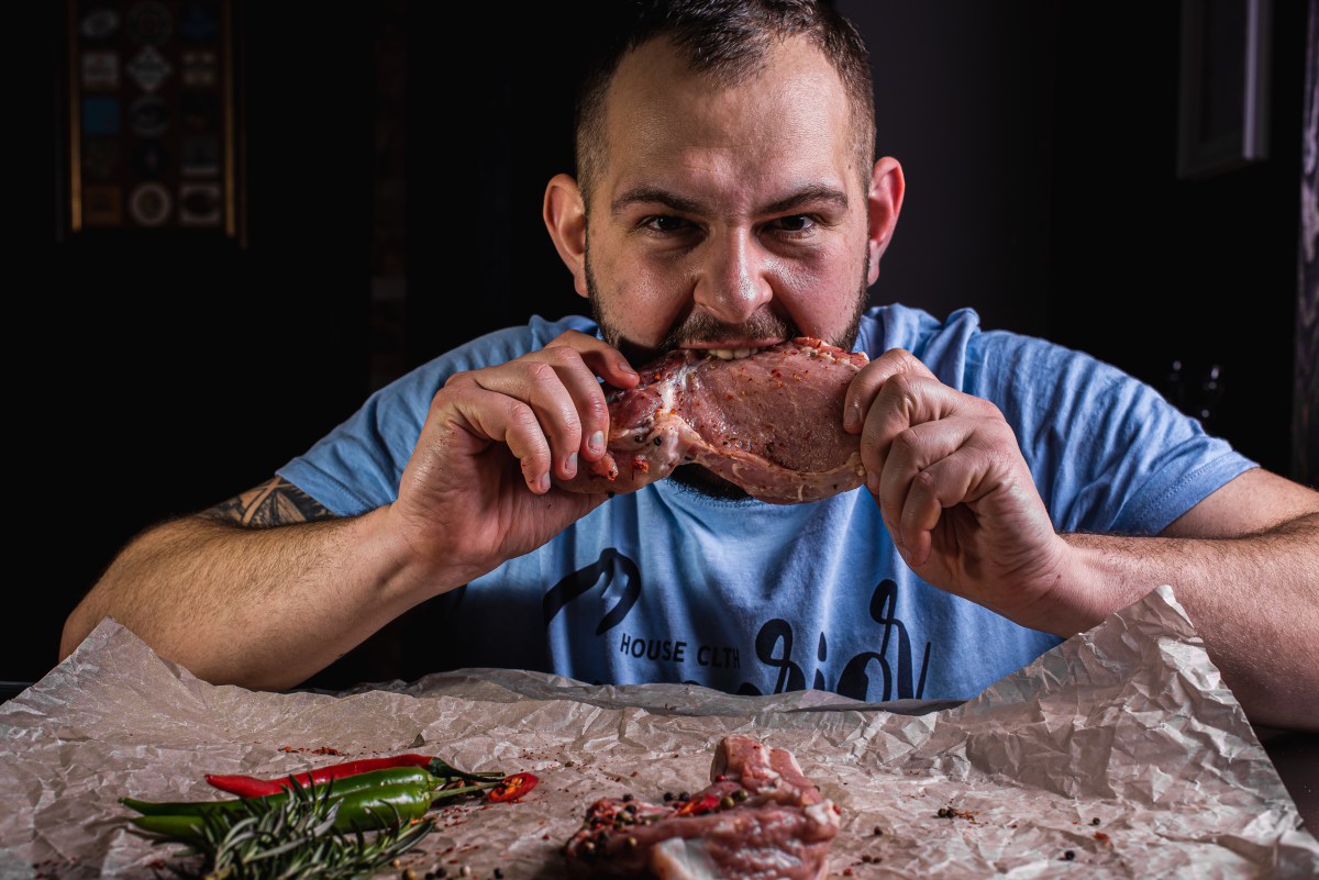 Mann beißt in rohes Fleisch