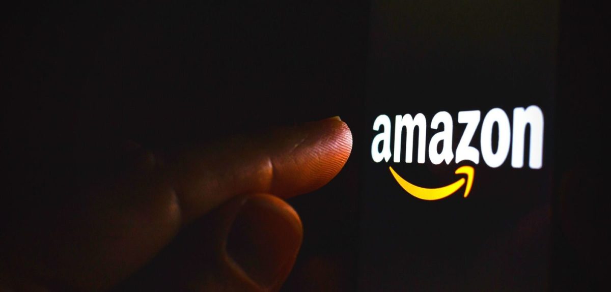 Ein Finger zeigt auf das Amazon-Logo auf einem dunklen Bildschirm.