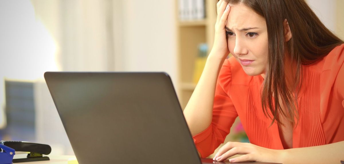 Frau sitzt frustriert vor einem Laptop.