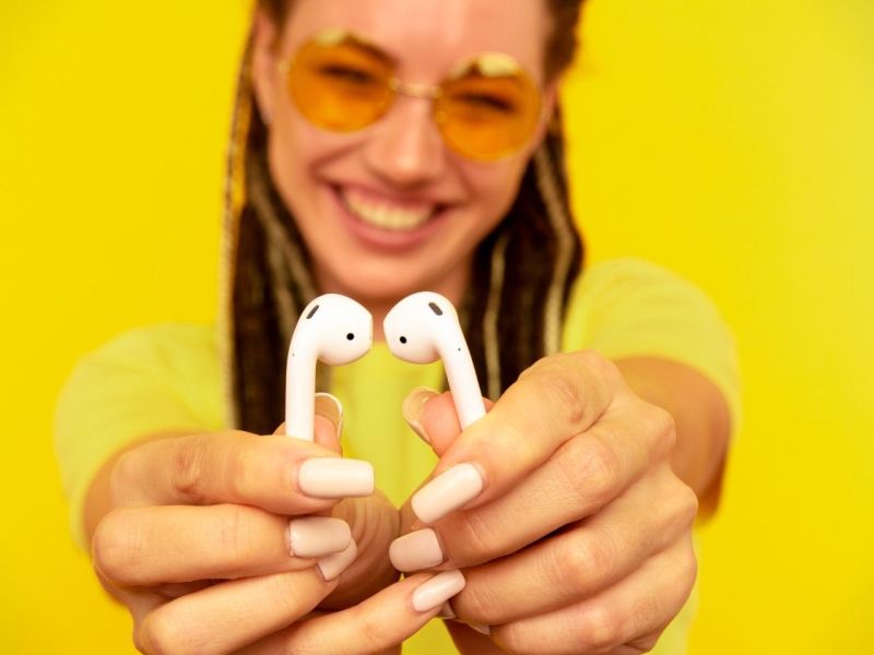 Frau hält AirPods in die Kamera