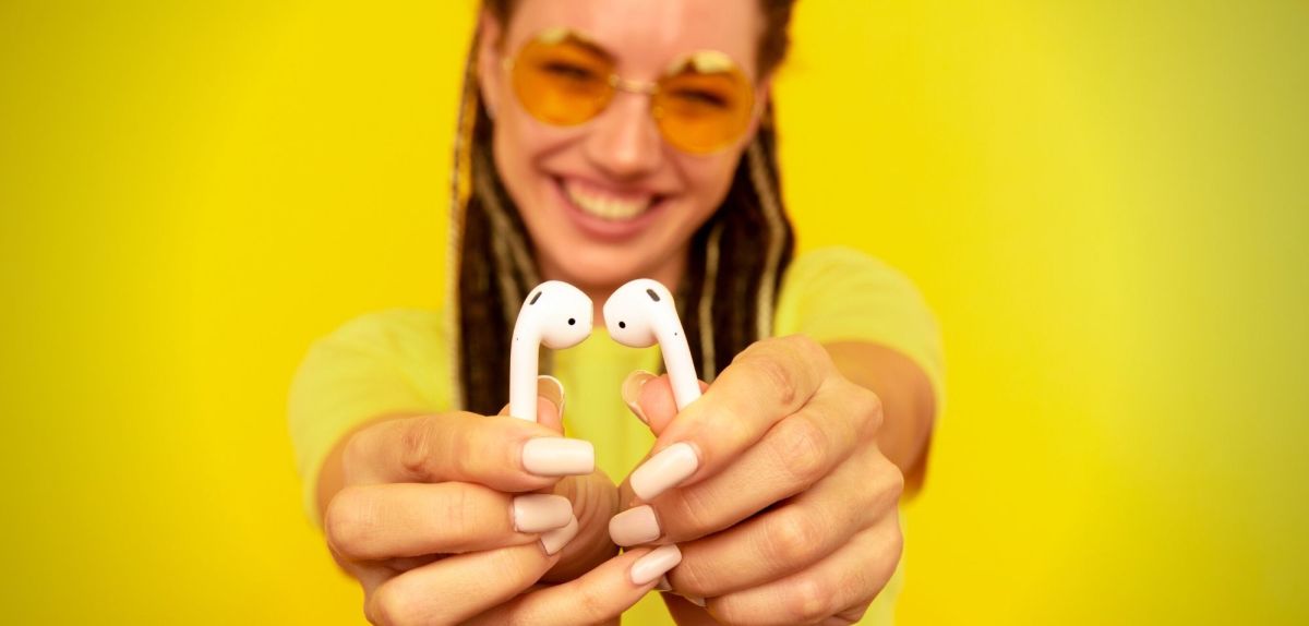 Frau hÃ¤lt AirPods in die Kamera