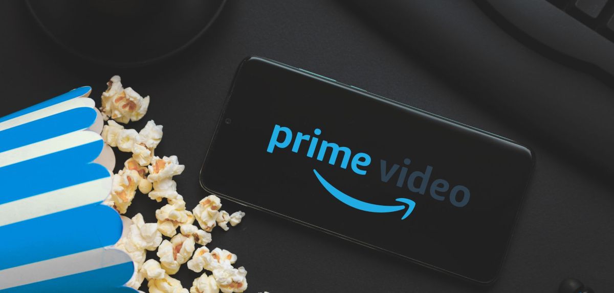 Logo von Amazon Prime Video auf einem Handy, daneben eine TÃ¼te Popcorn.